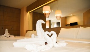 Habitación de hotel con una cama bien hecha, un espejo grande y una lámpara de pared.