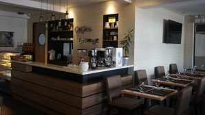 Un moderno salón de café con mostrador, zona de estar y diverso equipo para preparar café.