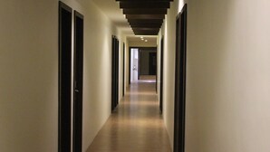 Un pasillo largo y estrecho con puertas a ambos lados y piso de baldosas.