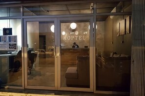 A hotel entrance with a reception desk, a waiting area with chairs, and a visible interior through the glass doors. - Koptel Budget Hotel (Kuching)