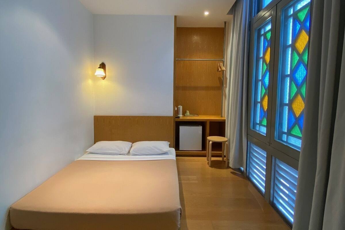 Un dormitorio con una cama, un escritorio, una silla y una ventana con vidrieras.