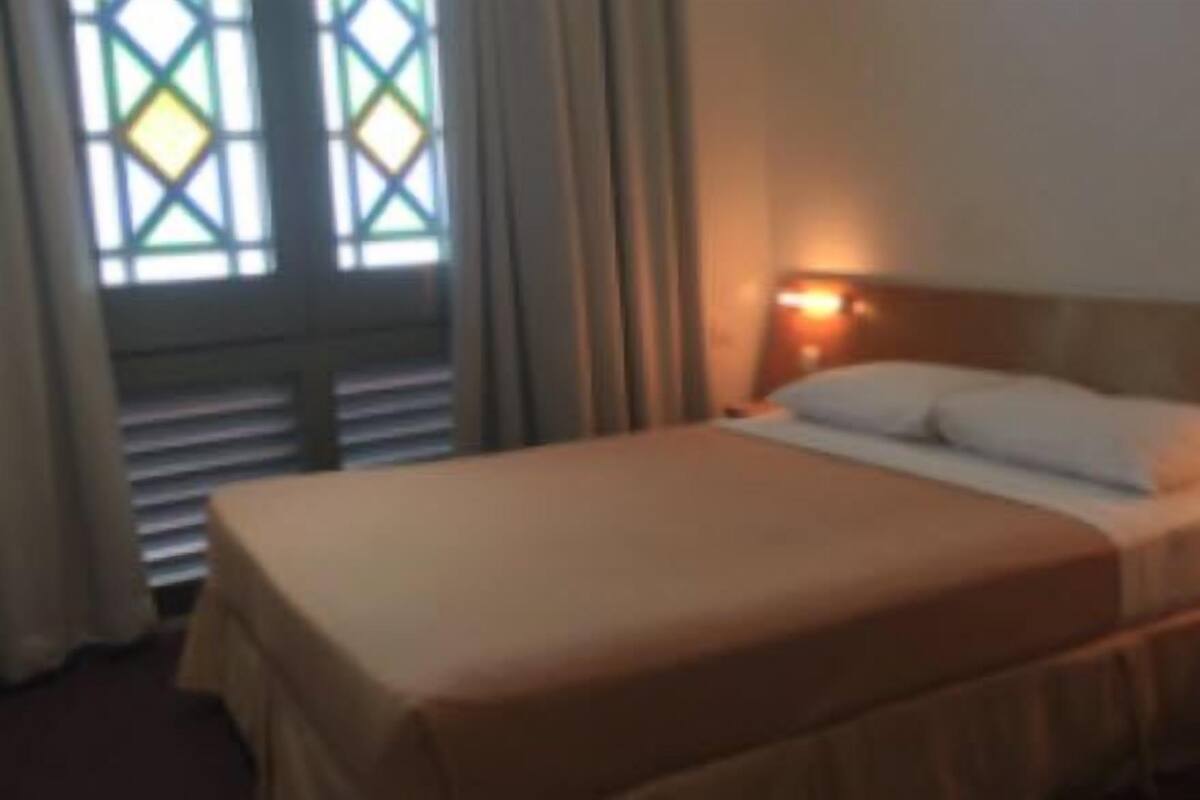 Una habitación de hotel con una cama, cortinas y un ventanal con un diseño geométrico.