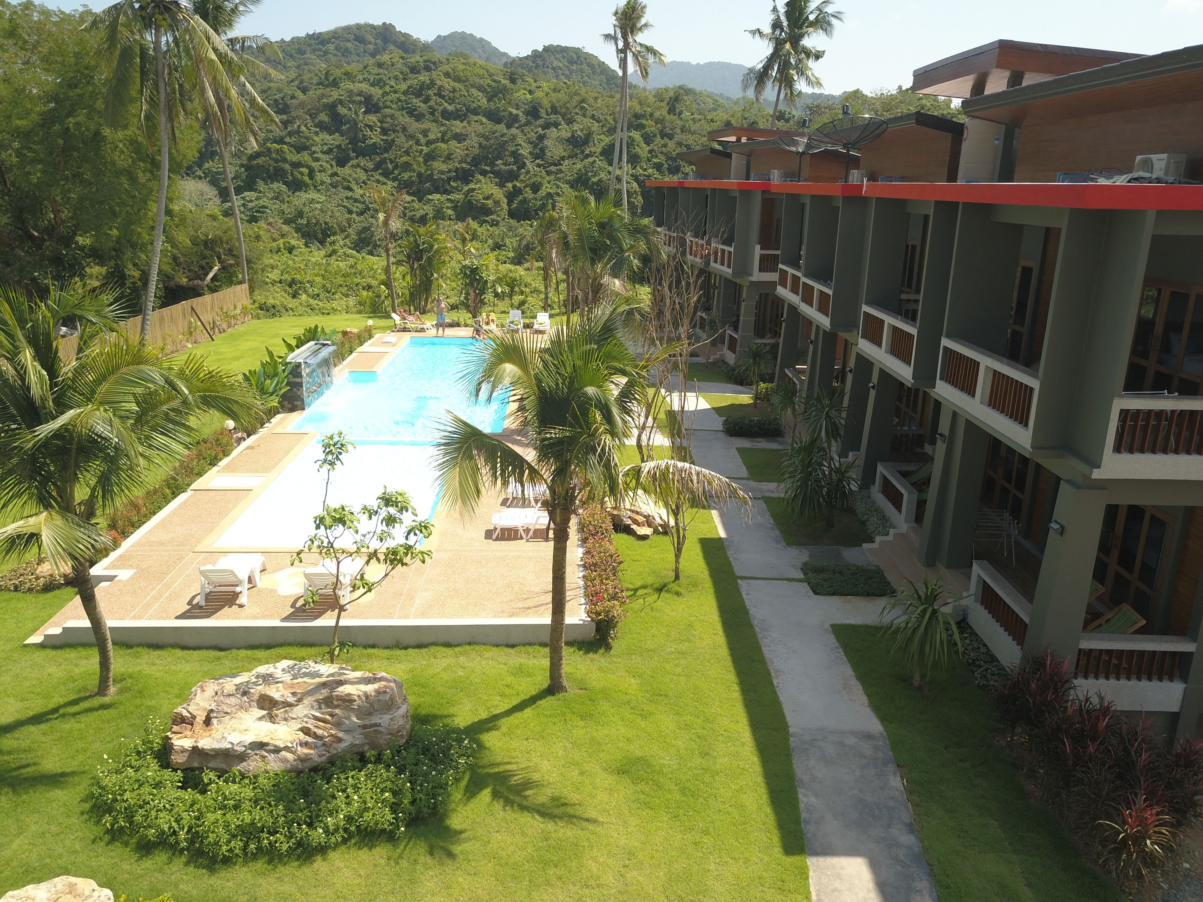 Um resort com piscina, palmeiras e montanhas ao fundo.