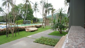 A landscaped garden with a pool, palm trees, and a waterfall. - Lanta Infinity Resort (Ko Lanta)