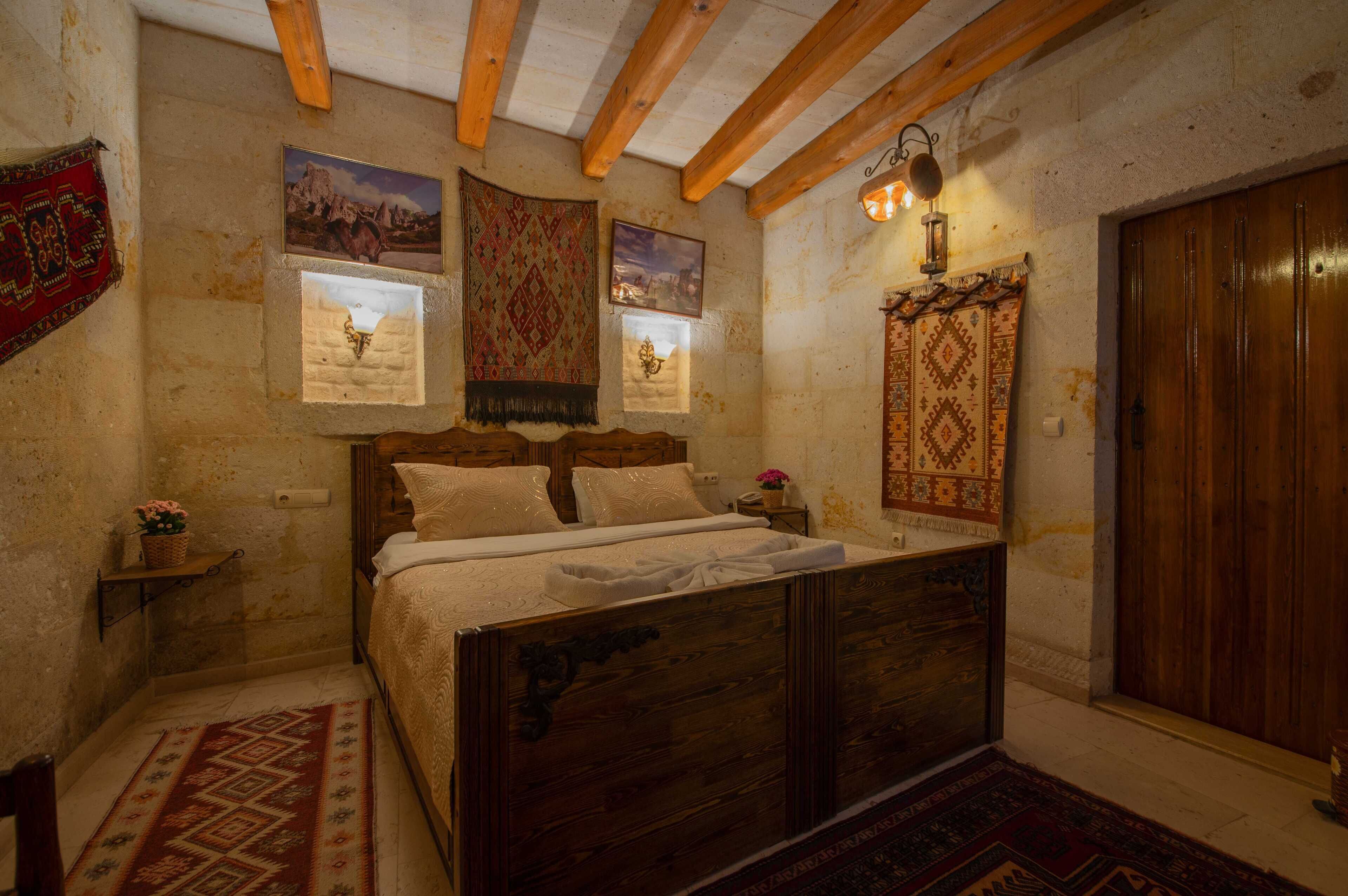 Un dormitorio con una cama de madera, una mesita de noche, una lámpara de pared y una puerta.
