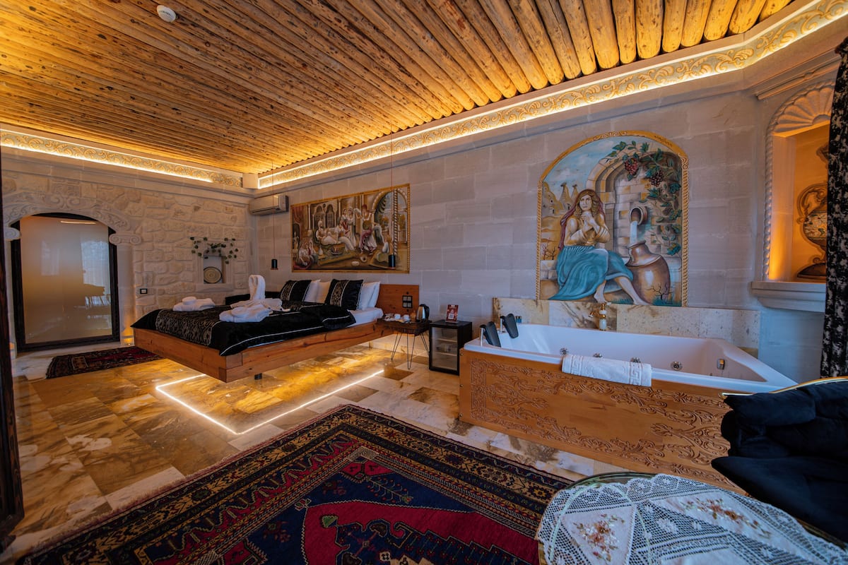Quarto com cama, banheira, um grande painel na parede e tapete estampado.