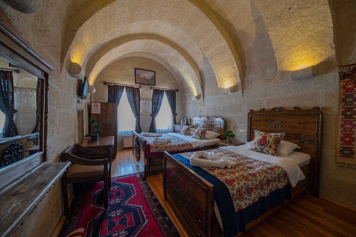 Quarto tradicional com duas camas de madeira, um banco e um espelho.