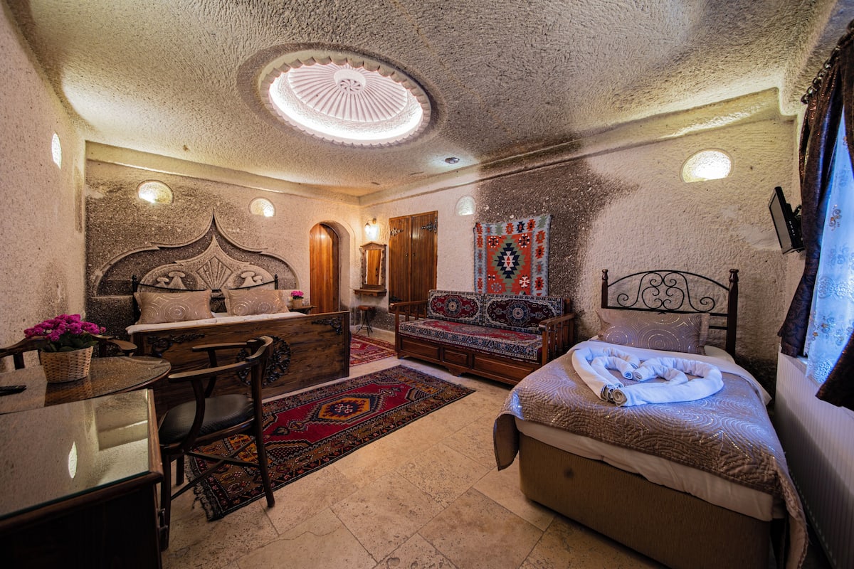 Quarto com cama, sofá, mesa de jantar e lustre.