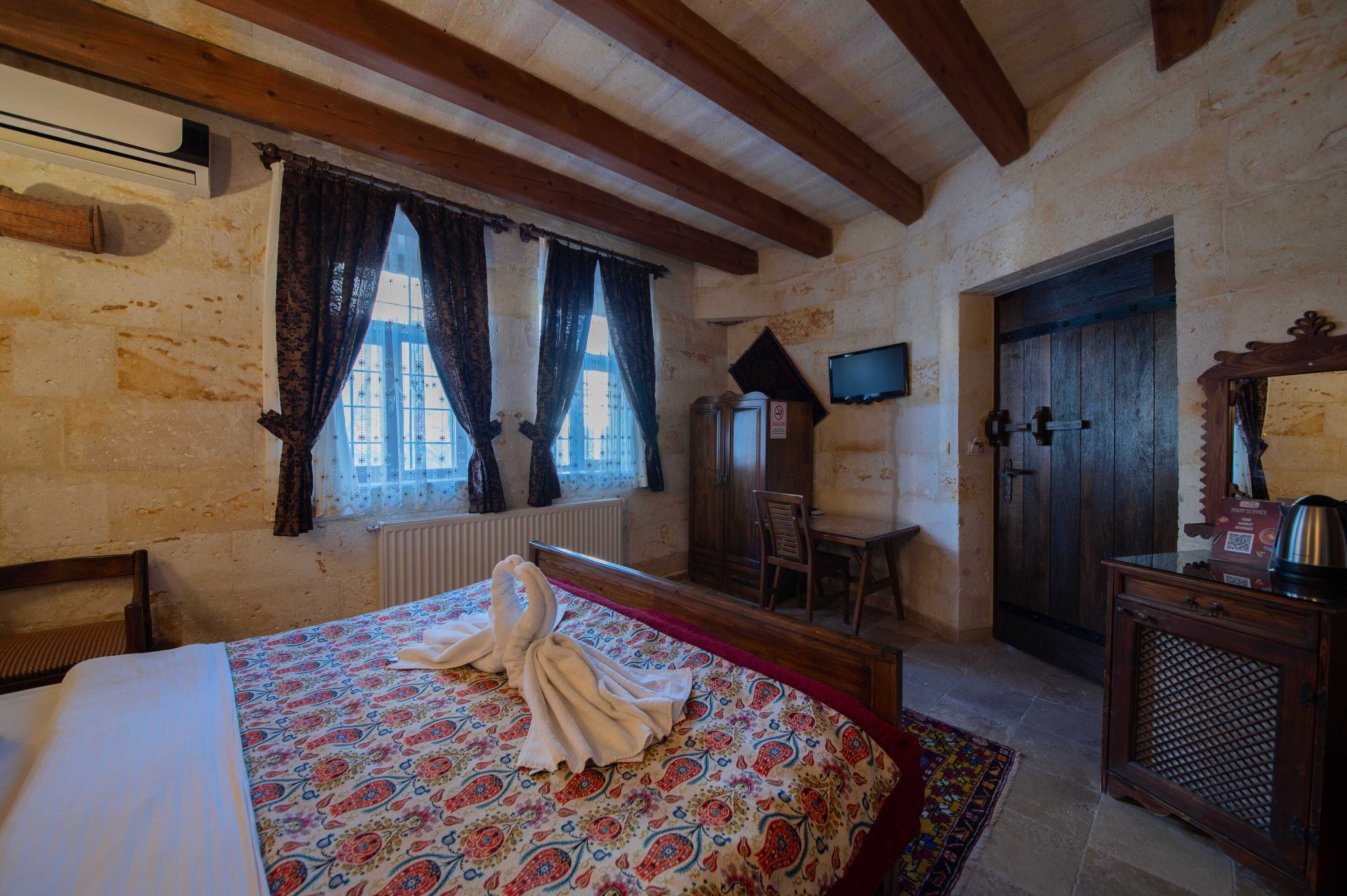 Una habitación con una cama, una silla de madera, un escritorio, un televisor y una puerta.