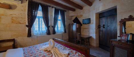 Una habitación con una cama, una silla de madera, un escritorio, un televisor y una puerta.