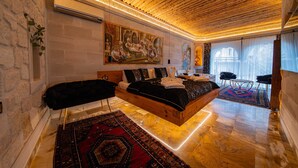 A spacious bedroom with a large bed, a wooden ceiling, and a large painting on the wall. - Safran Cave Hotel (Nevsehir)