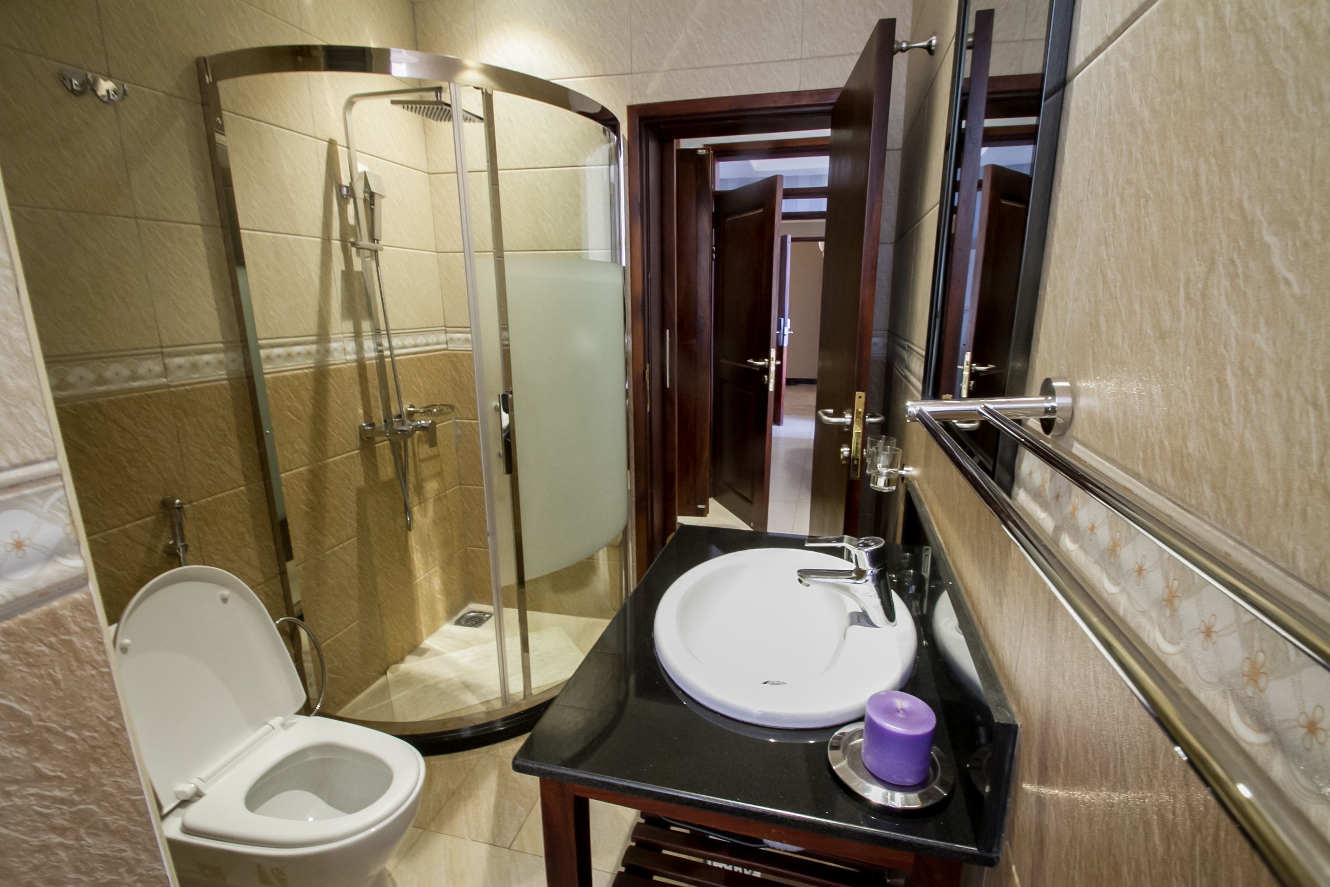 A bathroom with a glass-enclosed shower, a white sink with a mirror, and a toilet.