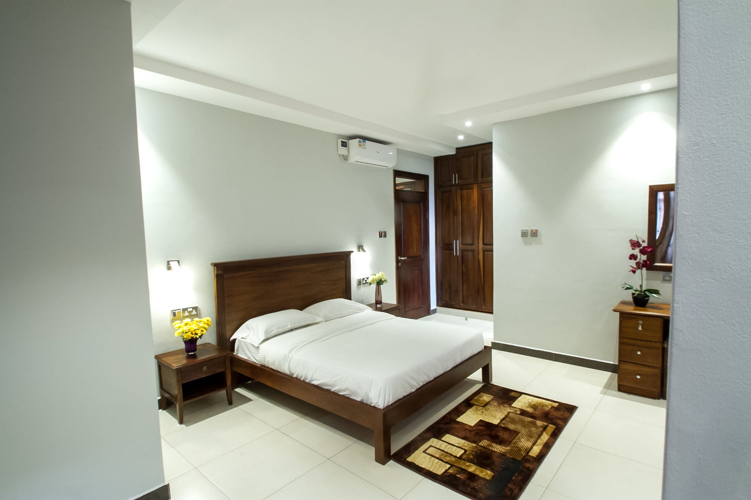 Un dormitorio con cama, mesita de noche, cómoda y espejo.
