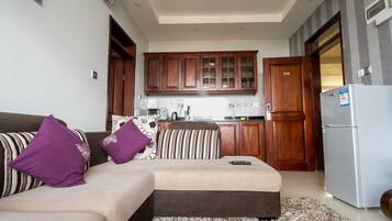 A living room with a sofa, pillows, a remote control, and a rug.