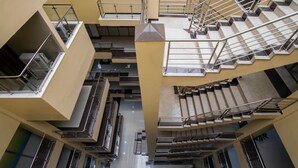 Et mere niveauer bestående interiør med en central trappe, flere balkoner og et moderne arkitektonisk design.
