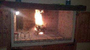 Une cheminée avec un feu qui crépite à l’intérieur, entourée de murs en briques.
