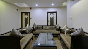 A room with a sofa set, two armchairs, a coffee table, and two doors with geometric designs. - Hotel Emporio (New Delhi)