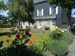 A stone building with a garden in front, outdoor seating, and a clear sky. - Le Tertre (La Feuillie)