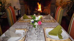 A dining table set for four with a fireplace in the background. - Le Tertre (La Feuillie)