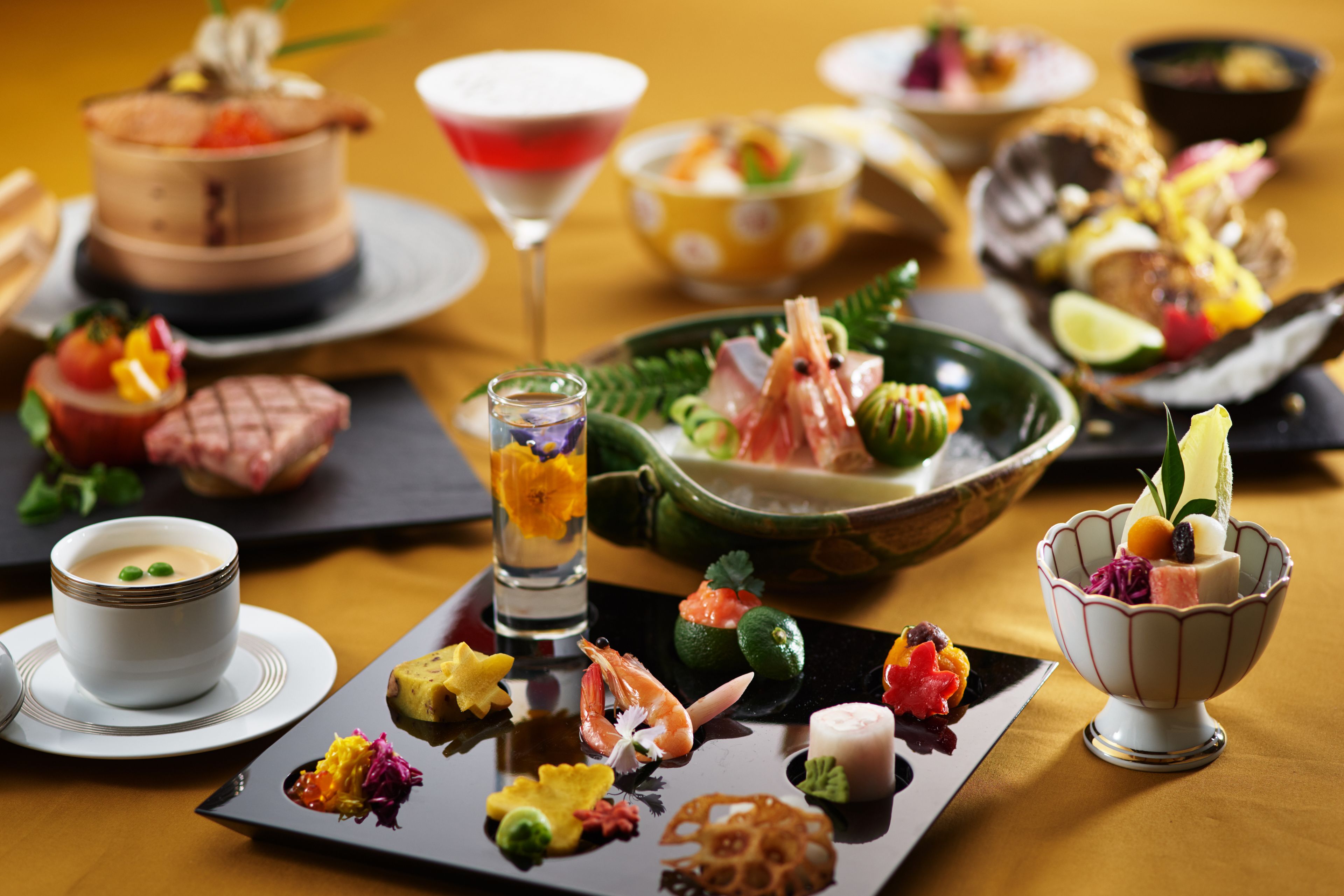 A variety of dishes and drinks on a table, including seafood, fruits, and a dessert.