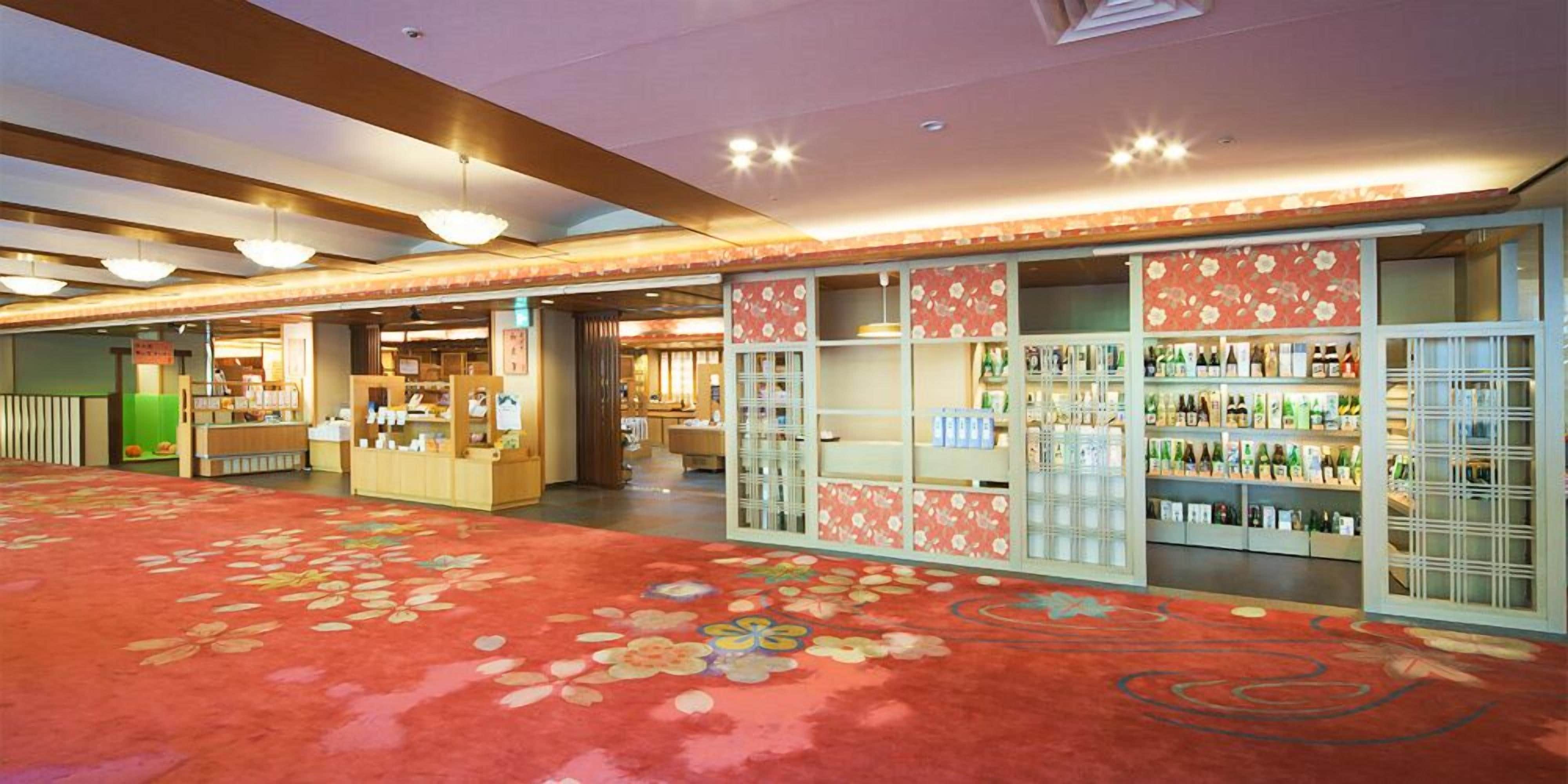 A hotel lobby with a floral carpet, a reception desk, and a bar area with shelves of bottles.