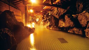 Un área de spa con suelo de baldosas, vigas de madera y grandes rocas.