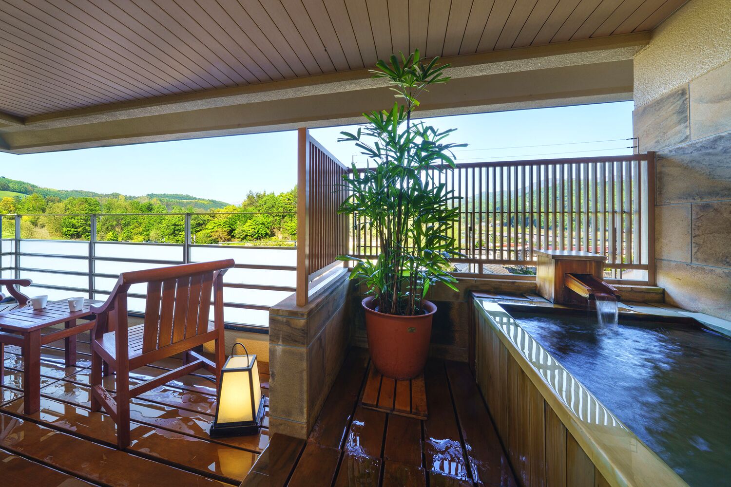 A wooden deck with a hot tub, a potted plant, and a bench.