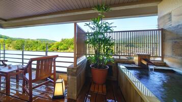 A wooden deck with a hot tub, a potted plant, and a bench.