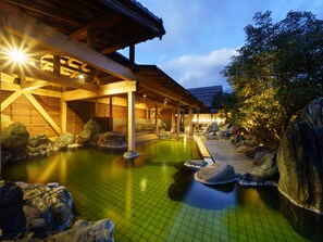 A traditional Japanese onsen with a wooden structure and a stone pathway leading to the hot spring area.