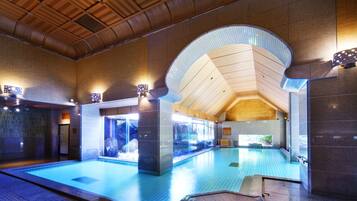 Una amplia piscina interior con techo de madera y paredes de piedra.