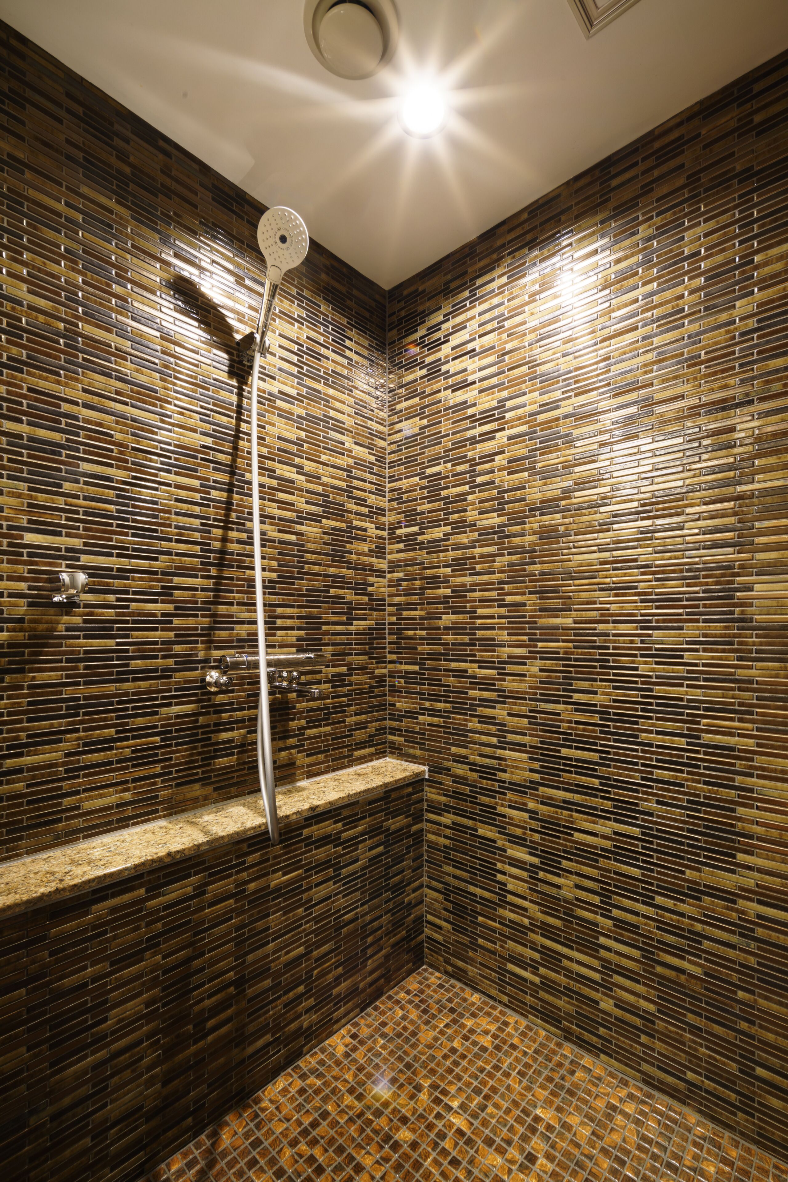 Un baño con ducha, paredes de azulejos e iluminación en el techo.