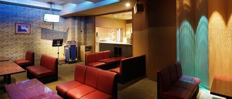 A hotel lobby with red leather seating, a reception desk, and a visible kitchen area.