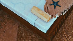 A bed with a brown blanket, a starfish decoration, and a wooden headboard. - Coco Beach Hotel (Jambiani)