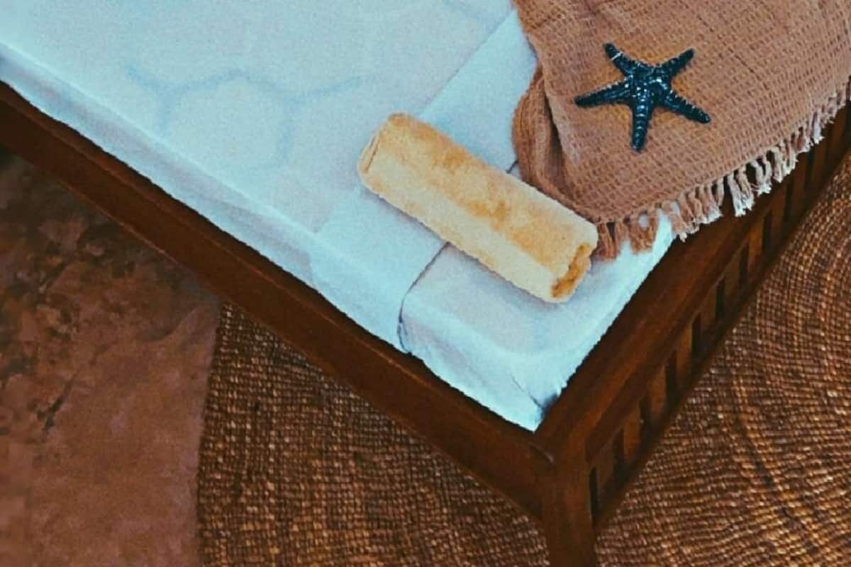 A bed with a brown blanket, a starfish decoration, and a wooden headboard.