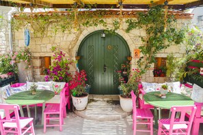An outdoor seating area with tables and chairs, a green door, and potted plants. - Apaz Alacati Hotel (Cesme)