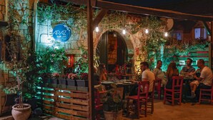 An outdoor dining area with stone walls, potted plants, and a sign for APAZ butik hotel. - Apaz Alacati Hotel (Cesme)