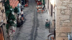 A narrow street with buildings on either side, some with balconies and outdoor seating. - Apaz Alacati Hotel (Cesme)