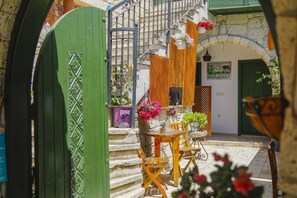 A courtyard with a wooden table and chairs, a green gate, and a stone wall. - Apaz Alacati Hotel (Cesme)