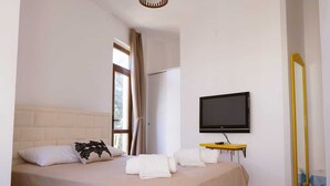 A bedroom with a bed, a TV, a mirror, and a window with curtains. - Apaz Alacati Hotel (Cesme)