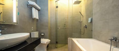 Un baño moderno con una bañera grande, ducha con mampara de vidrio, inodoro y lavabo con espejo.