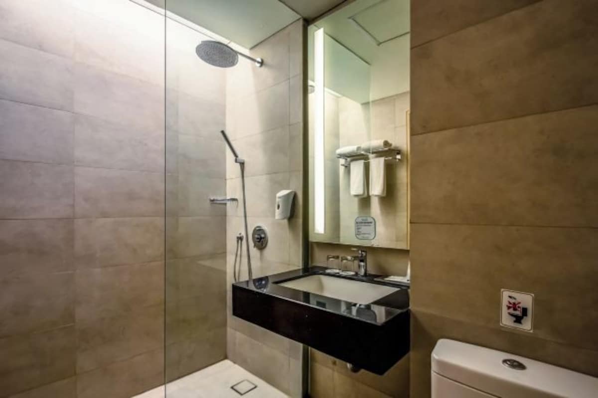 Un baño moderno con ducha acristalada, un lavabo negro y un inodoro.