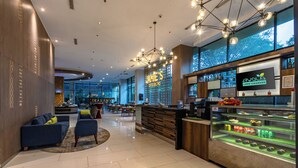 Um lobby de hotel moderno com área de bar, assentos e uma grande janela com vista.