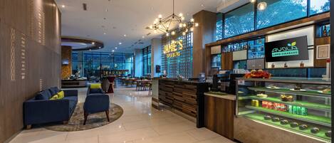 A modern hotel lobby with a bar area, seating, and a large window offering a view.