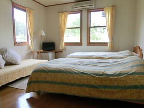 A room with two beds, a desk with a television, and an air conditioning unit. - Pension COME (Minamiuonuma)