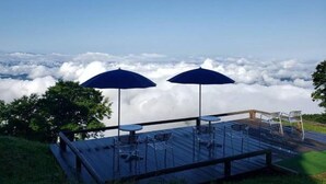 Eine Terrasse mit Tischen und Stühlen mit Blick auf eine Wolkenmeer.