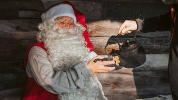 Une personne déguisée en Père Noël, tenant un pot noir doté d'une anse.