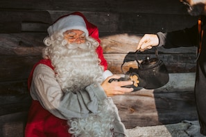 Una persona disfrazada de Papá Noel sosteniendo una olla negra con asa.