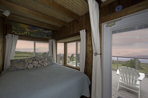 A bedroom with a large bed, a view of the outdoors, and a balcony with chairs. - Heaven on Earth in Upcountry Maui (Kula)