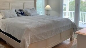 Un dormitorio con una cama grande, un ventilador de techo y vistas al exterior por una ventana.