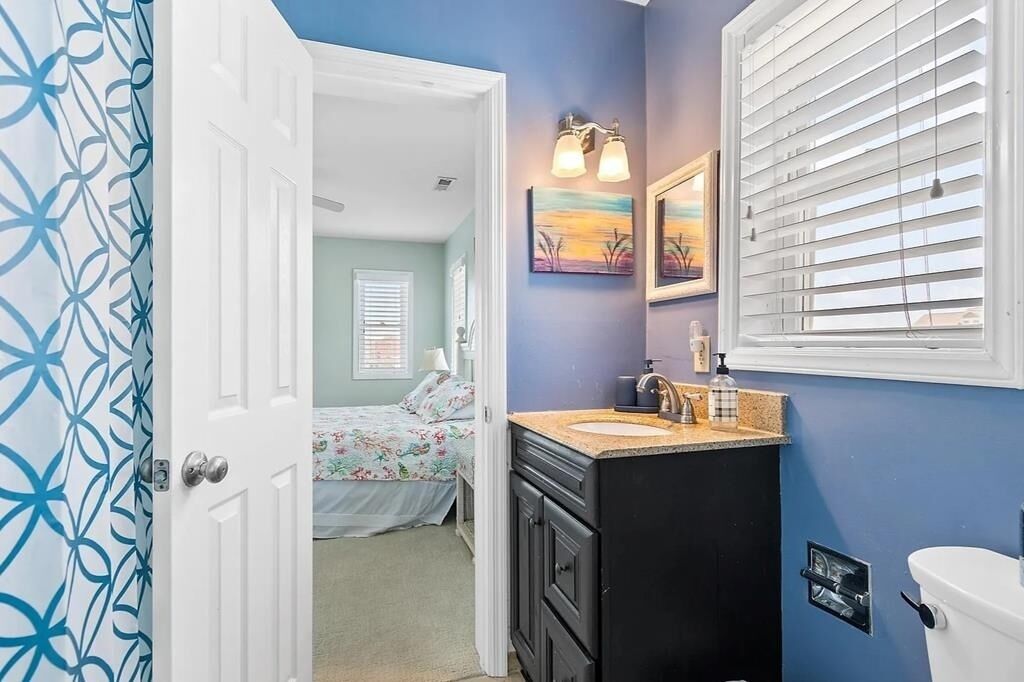 Une salle de bain avec un mur bleu, une porte blanche, un lavabo avec un plan de travail et des toilettes.
